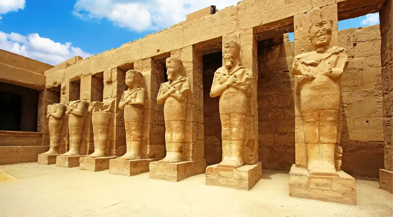 Row of ancient Egyptian pharaoh statues inside a stone temple